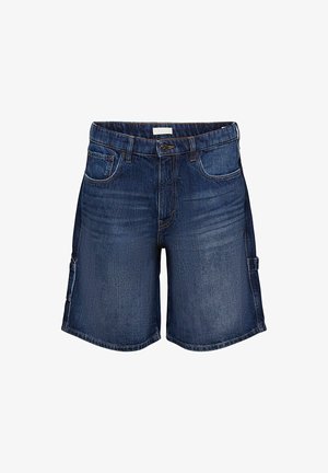 Szorty jeansowe w ciemnym niebieskim kolorze, o luźnym kroju, z bocznymi kieszeniami i brzegiem z lekkim postrzępieniem. Połączone z zielonym, graficznym t-shirtem i białymi trampkami.