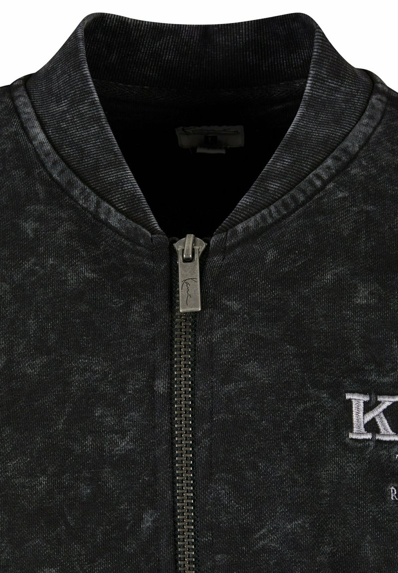 Giacca bomber nera con finitura testurizzata, colletto a coste, zip completa e logo ricamato bianco sul davanti.
