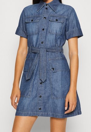 Vestido de camisa de mezclilla en azul oscuro, con mangas cortas, cuello, cierre de botones en el frente, dos bolsillos en el pecho y un cinturón de tela en la cintura.