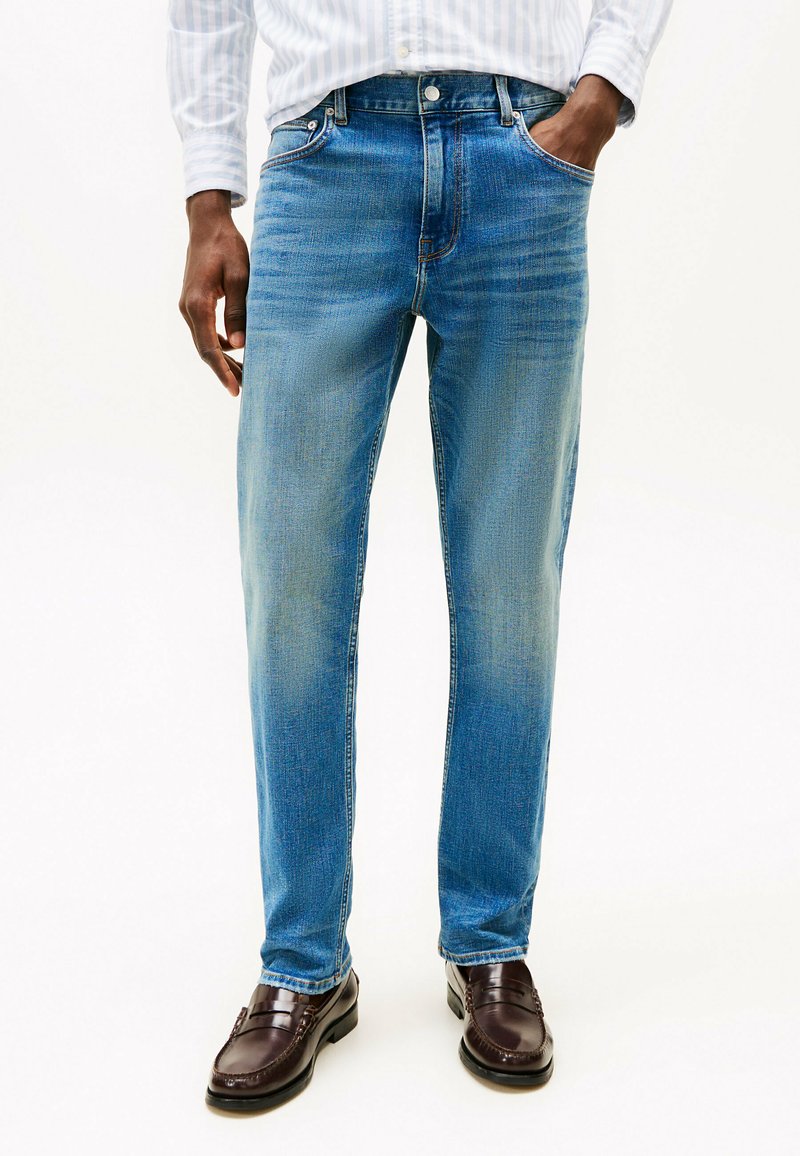 Jeans in denim blu chiaro con gamba dritta, con cuciture a contrasto, cinque tasche e chiusura a bottone.