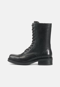 Black leather lace-up ankle boot with a rounded toe, textured surface, and a low stacked heel. Features 10 eyelets and reinforced stitching.