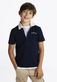 Polo di colore blu navy con colletto bianco a righe, maniche corte e piccolo logo sul petto. Realizzato in cotone strutturato.