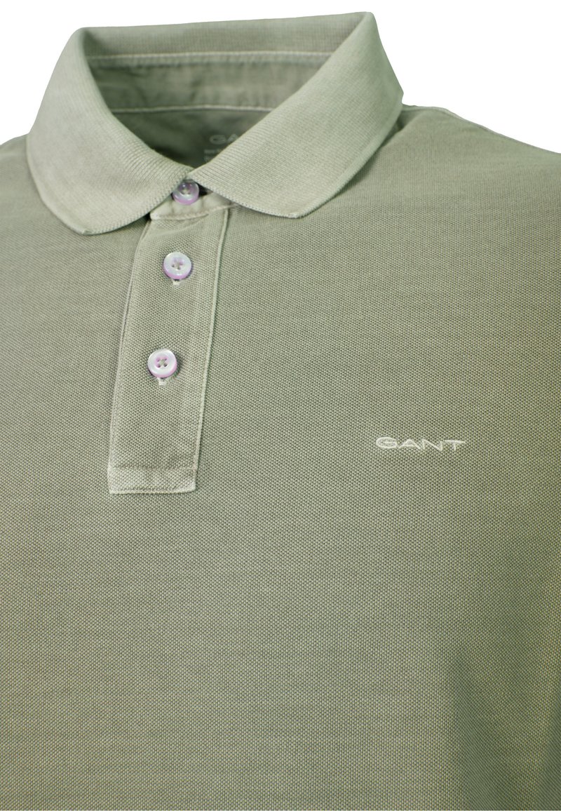 Lys grøn polo med ribbet krave, tre hvide knapper og lille hvidt GANT-logo på brystet.
