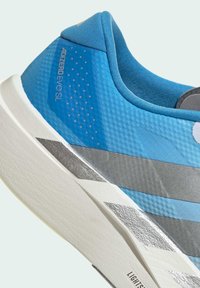 Blauer Sportschuh mit silbernen Akzenten. Texturierter Oberstoff und glatte Überzüge, gedämpfte Sohle und reflektierende Elemente. Modell: Adizero Evo SL.