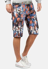 Shorts cargo en bleu, orange et noir avec un design éclaboussé de peinture. Comprend plusieurs poches, des zips et un texte blanc contrastant.