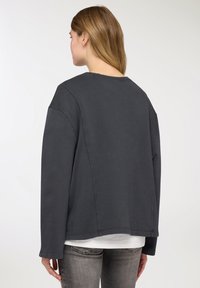 Felpa oversize grigio scuro con scollo rotondo, spalle scese e vestibilità ampia, realizzata in morbido tessuto di cotone.