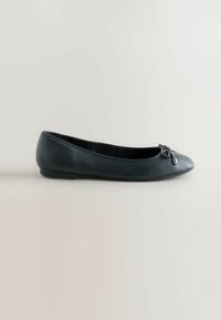 Schwarze Leder-Ballerinas mit abgerundetem Zeh, minimaler Naht und einer dekorativen Schleifenakzent auf der Vorderseite. Glatte Textur, flache Sohle.