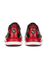 Zapatillas deportivas negras y rojas con parte superior texturizada, talón acolchado, logotipo prominente y suela blanca contrastante.