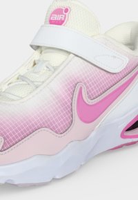 Λευκό και ροζ αθλητικό παπούτσι Nike Air Max με ύφασμα δίχτυ, ροζ λογότυπο swoosh και λευκή λωρίδα βέλκρο πάνω από τα κορδόνια.