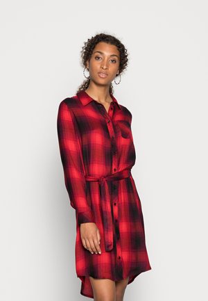 Robe chemise à carreaux rouges et noirs en tissu doux, avec un bouton sur le devant, des manches longues et une ceinture nouée à la taille.