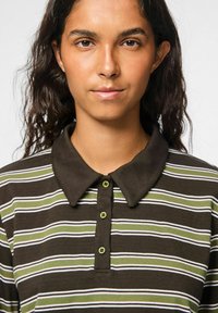 Bruine en groene gestreepte polo met een kraag en drie knopen. Heeft een gladde textuur en een klassiek ontwerp.