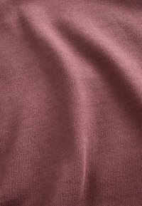 Minkštas mauve spalvos megztas audinys, su tekstūruotu, briaunotu raštu, užfiksuojančiu smulkias vaguotes ir lygų paviršių.
