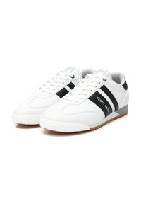 Scarpe da ginnastica bianche con strisce nere, con tomaia in pelle liscia, suola piatta, punta tonda e occhielli argentati per i lacci.