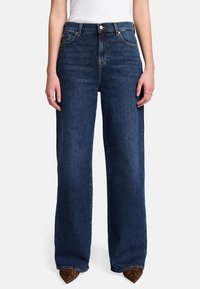 Breda mörka denimjeans med hög midja, med klassisk femficksdesign och slät finish. Kombinerade med spetsiga leopardmönstrade klackar.