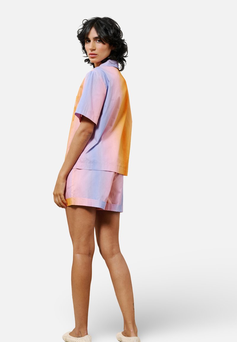 Kurzärmliges, farblich abgesetztes Shirt und passende Shorts in pastellfarbenem Rosa, Orange und Blau. Der Stoff scheint glatt und leicht zu sein.