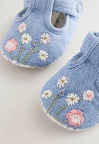 Jeansbabyskor med blommönster i rosa, vitt och blått. Har en rund tå och remknäppning, med en texturerad sula.