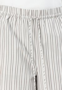 Pantaloni del pigiama a righe in bianco e marrone chiaro, con vita elastica e cordoncino, realizzati in morbido tessuto.