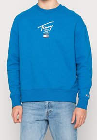 Helle blaue Crewneck-Sweatshirt aus weicher Baumwolle. Verfügt über ein weißes Logo mit Städtenamen, gerippte Bündchen und Saum.