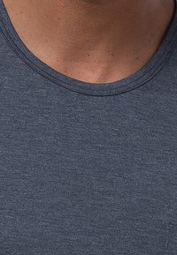 Marineblauwe gestructureerde katoenen t-shirt met een ronde hals. Close-up laat het oppervlak van de stof en de stikdetails zien.