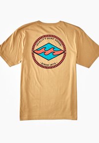 Camiseta de algodón beige con un gráfico circular en rojo y turquesa que presenta olas y el texto "Productos de Surf de Calidad Desde 1973" en la parte superior.