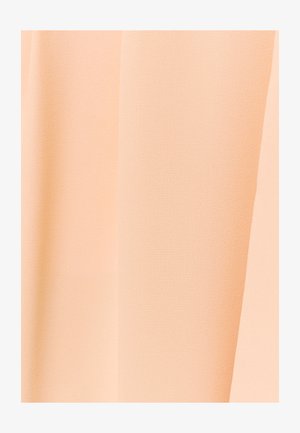 Peene tooniga pehme riide lähivõte, millel on õrn diagonaalne koeskeem ja õrnad voldid.