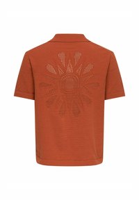 Polo manches courtes couleur rouille avec un motif de rayons de soleil perforé centré dans le dos.