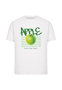 T-shirt en coton blanc avec un graphisme de pomme verte, un texte en surdimensionné portant le mot "POMME" et le slogan "Doux. Croquant. Simple." en vert.