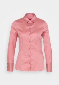 Camicia rosa con bottoni, maniche lunghe, realizzata in tessuto morbido. Presenta un colletto a punta e polsini con dettagli di bottoni.