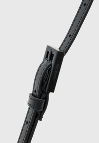 Cintura in pelle nera con una superficie liscia, dotata di una fibbia rettangolare in metallo nero e fori per la regolazione lungo tutta la sua lunghezza.