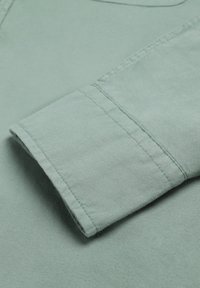 Lichtgroene, lange mouwen met manchetten van een shirt, met een gladde textuur en rechte stikseldetails. Katoenen stof met eenvoudige ontwerp elementen.