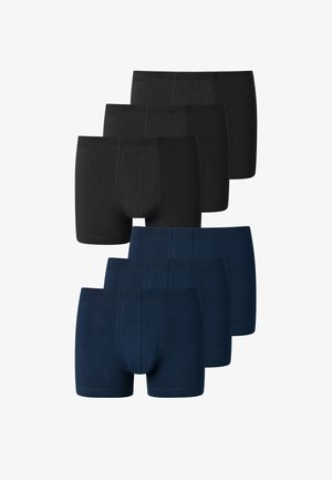 Sorte boxer shorts lavet af blødt stof, med en sømløs talje og tætsiddende pasform, set iført af en person mod en neutral baggrund.