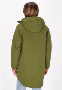 Ilgas alyvuogių žalias parka su gobtuvu, elastiniais rankogaliais ir kreiviu apvadu. Lygi tekstūra, pritaikytas sijonas ir minimalūs detalių akcentai.