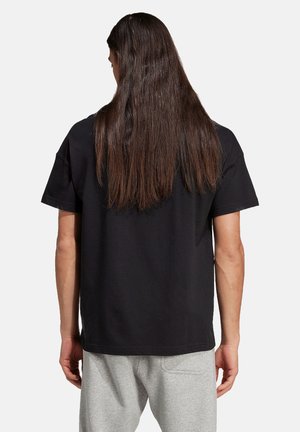 T-shirt in cotone nero con una vestibilità rilassata e maniche corte, dotata di un collo rotondo. Il tessuto appare morbido con una superficie liscia.