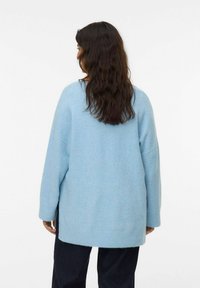 Lichtblauwe oversized trui van zacht materiaal, met een brede halslijn, verlaagde schouders en een langere achterzoom. Eenvoudig en strak ontwerp.