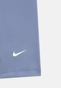 Top deportivo de Nike en tejido azul claro, con una textura suave y un logo blanco en la esquina inferior izquierda.