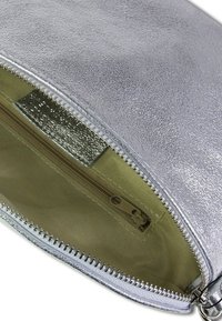 Zilveren metallic ritstas met een soepele textuur; de binnenkant heeft een beige stoffen voering en een klein ritsvakje.