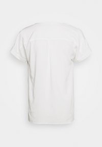 T-shirt bianco a maniche corte, in tessuto morbido, vestibilità rilassata, con cucitura a Y sulla schiena e leggero dettaglio a piega al centro.
