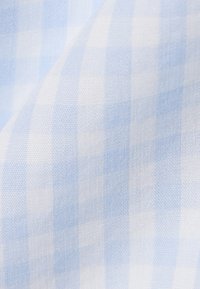 Tissu à carreaux bleu clair et blanc avec un tissage doux et fin et des plis subtils.