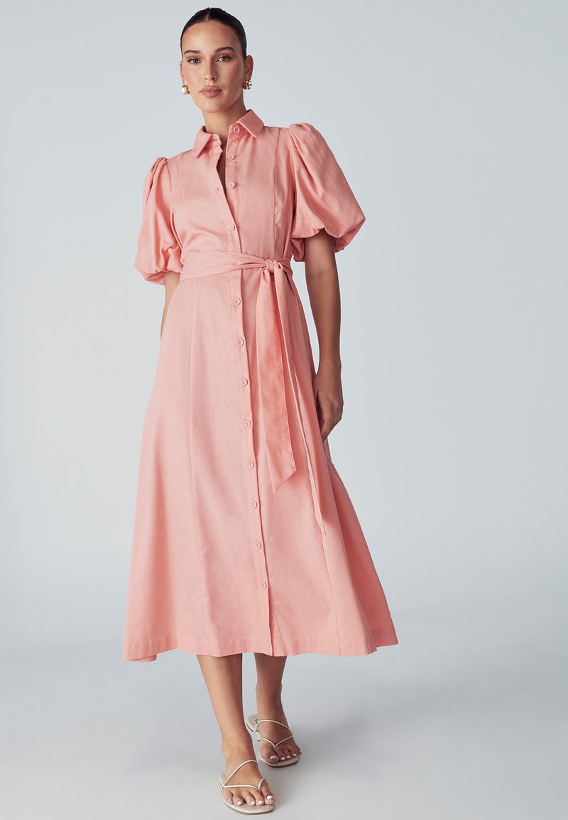 Ružičasta lanena midi haljina s nabranim rukavima, ovratnikom, prednjim kopčanjem na gumbe i vezanjem u struku. Glatka tekstura, ležeran dizajn.
