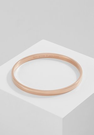 Rose gold bangle bracelet with a smooth, polished finish, featuring engraved "kate spade NEW YORK" inside. Simple, round design.