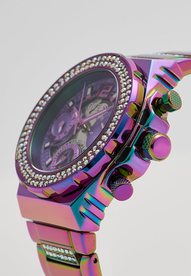 Montre métallique colorée avec une finition iridescente violette, des accents en cristal autour de la lunette et plusieurs cadrans de chronographe sur un bracelet à maillons.