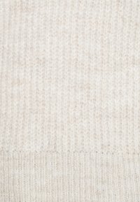 Pletený svetr z jemného krémového materiálu s texturovaným vzorem a vertikálními pruhy. Hladký povrch s mírnými barevnými variacemi.