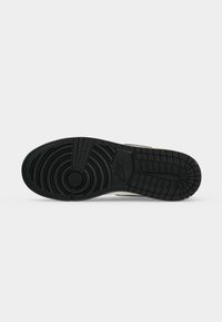 Μαύρη λαστιχένια σόλα ενός sneaker της Nike που δείχνει κυκλικά και ορθογώνια σχέδια πέλματος με το λογότυπο της Nike χαραγμένο κοντά στο κέντρο.