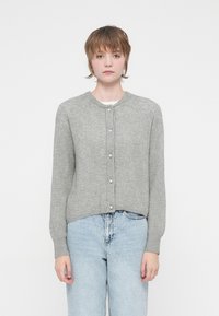 Cardigã cinza canelado com decote redondo, botões frontais e mangas longas, usado sobre jeans azul claros, num fundo branco simples.
