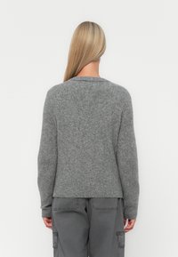 Grå strikkegenser med rund hals, ribbestrikket hem og avslappet passform. Myk tekstur med lange ermer, vist fra ryggen.