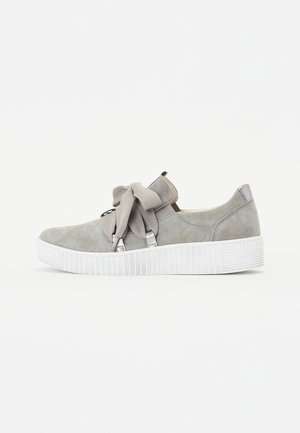 Grijze suède sneaker met een ronde neus, witte textuur zool en een grote strikdetail op de tong. Voorzien van metalen accenten.