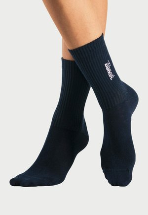 Navy Rippensocken mit einem einfarbigen Design. Sie verfügen über einen dicken, strukturierten Bund und dezente Markenkennzeichnung in heller Farbe in der Nähe des Knöchels.