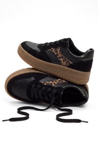 Paire de baskets noires avec semelles en gomme marron, détail côté imprimé léopard, lacets noirs et combinaison de cuir et de suède.