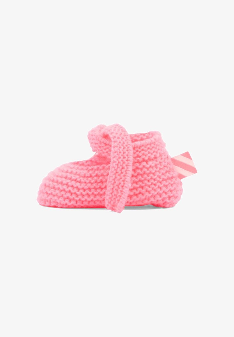 Chausson de bébé tricoté en rose doux avec une bride repliée et une étiquette en tissu rayé rose au talon, isolé sur fond blanc.