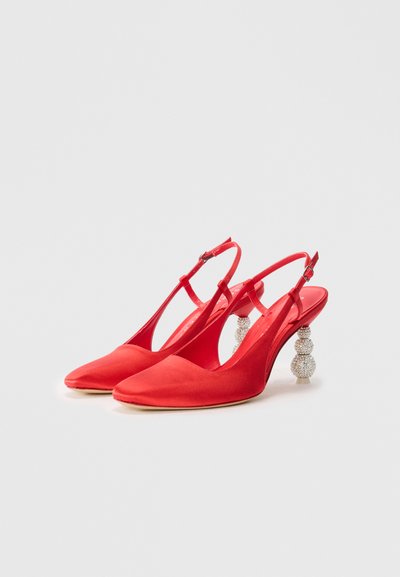 Red satin slingback heels with a pointed toe and a clear, jeweled ball-accented heel. Smooth texture and adjustable ankle strap.